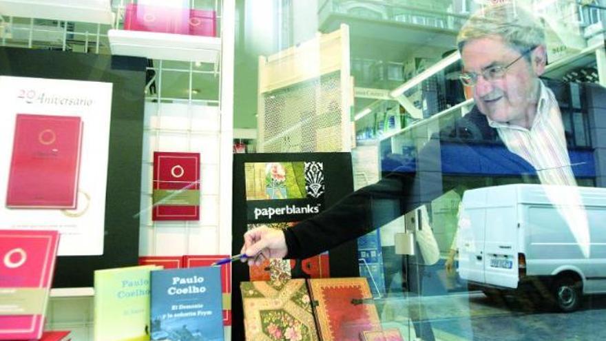 Víctor Núñez muestra uno de los libros de «Paulo Coelho» situados en el escaparate de su librería.