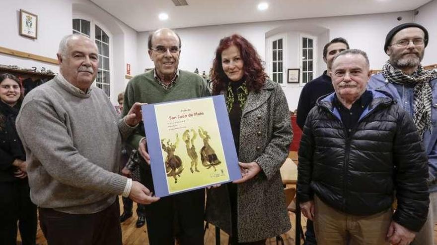 Klara Konkoly, con Belarmino Fernández (a su derecha) y otros vecinos, ayer, mostrando el cartel de la fiesta.