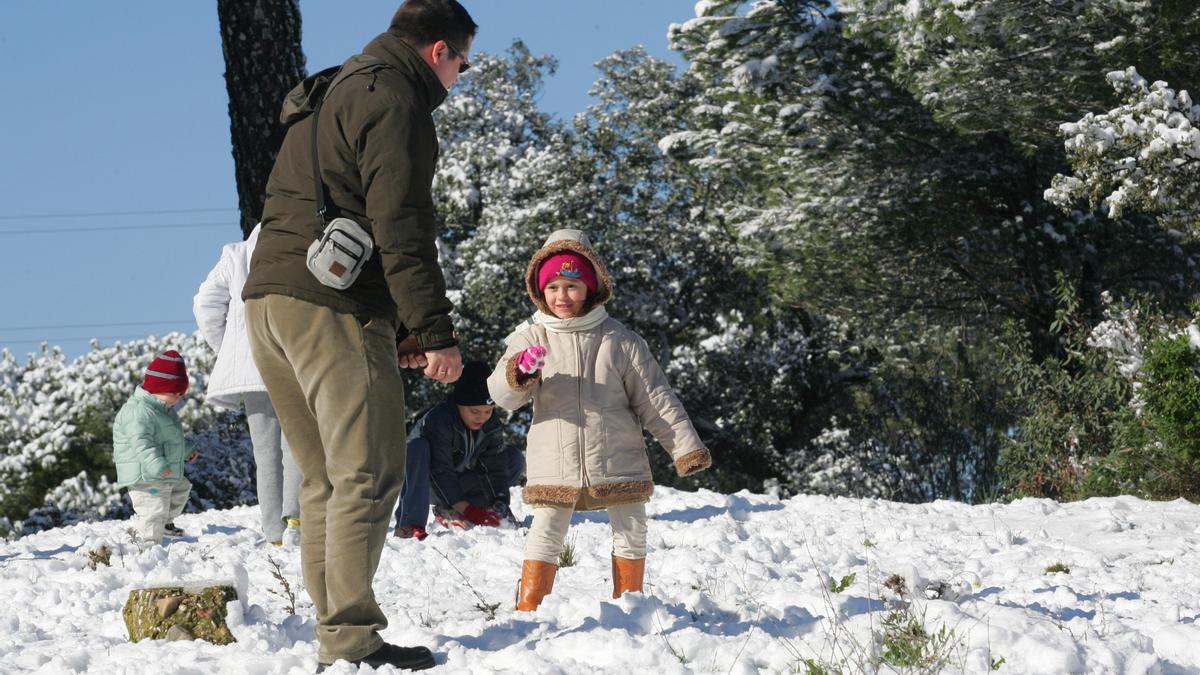 Un padre juega con su hija en la nieve.