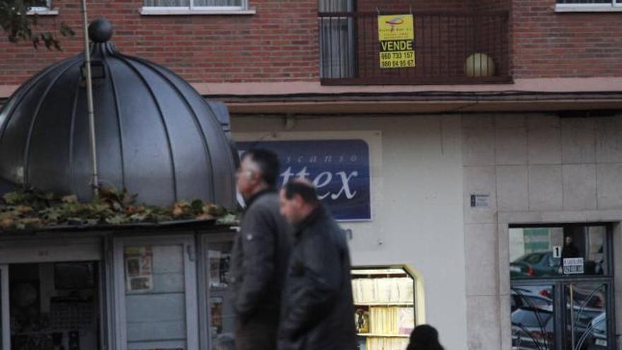 Dos personas pasan frente a un piso en venta en Zamora.