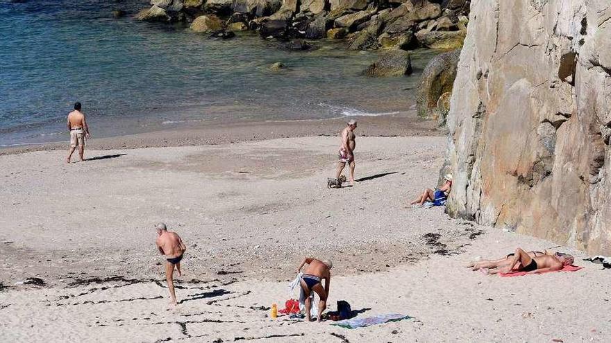Bañistas toman el sol y pasean en bañador, ayer, en la playa de As Lapas.