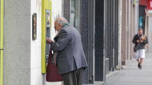 Un anciano saca dinero de un cajero