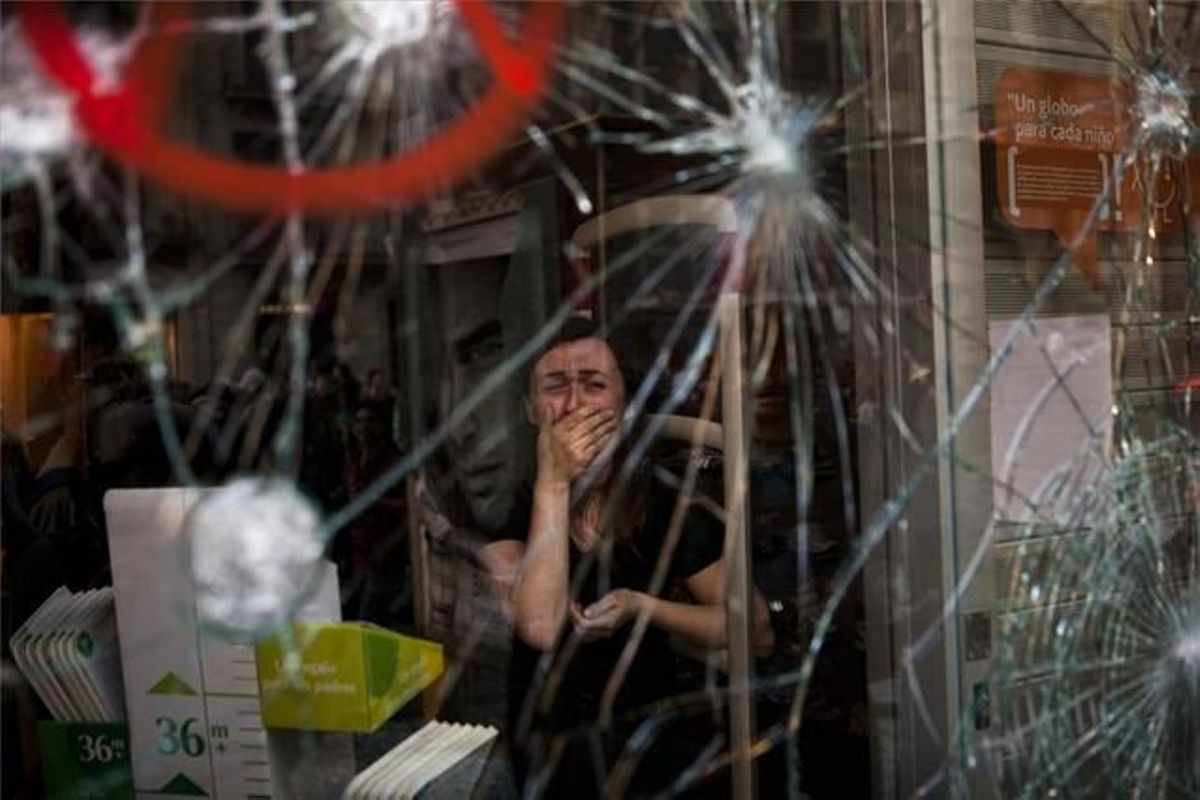 Mireia Arnau, de 39 anys, darrere del vidre trencat de la seva botiga durant els incidents a Barcelona de la vaga general del 29-M. Tercer Premi en la categoria ’Temes Contemporanis’.