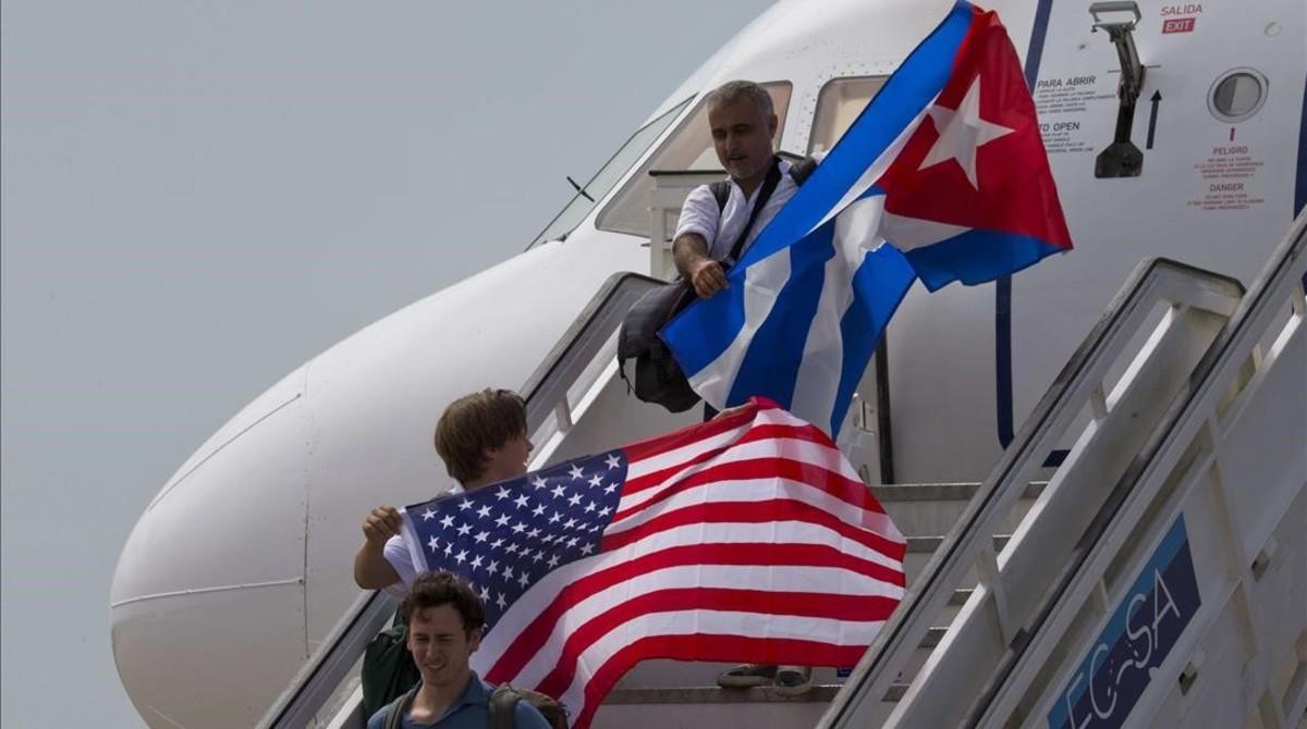 Pasajeros con banderas de EEUU y Cuba en un vuelo llegado al aeropuerto de Santa Clara.