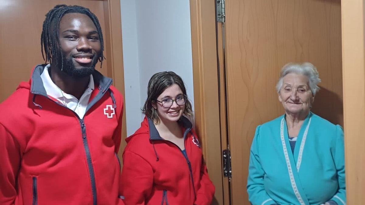 Dos voluntarios entregan la cena a una vecina.