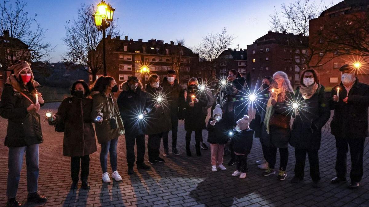 Por la izquierda, Noelia Moles, Isabel Gil, Paula Gil, Antonio Meire, Antonia García, David Cabal, Mara González, Olaya Cabal, Lucía Cabal, Ramón Victorero, Rosa de la Torre, las pequeñas Joana y Yanira Lobo, Adela García, Marga Sancho, Paquita Alija y Gonzalo Díaz, concentrados en la tarde de ayer con velas y linternas en la plaza de la Araña de Las Campas. | Irma Collín