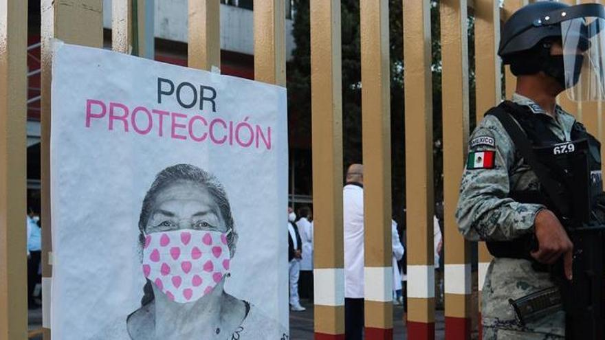 Soldados hacen guardia mientras personal médico hace fila para ser vacunado contra la covid-19 en el Hospital General, en Ciudad de México.