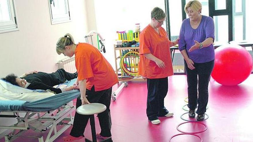 Dos pacientes son atendidas por el personal en la sala de rehabilitación.