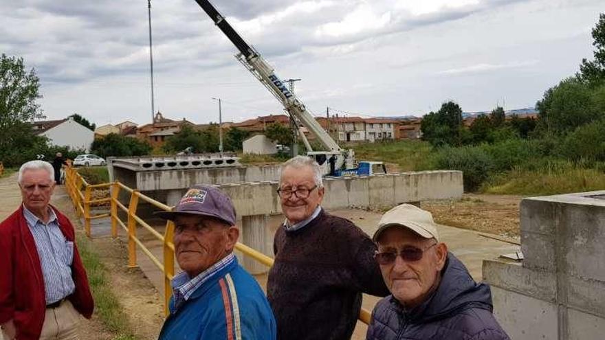 Varios vecinos observan los trabajos de las vigas de hormigón para la plataforma del puente sobre el arroyo del Regato, en Uña de Quintana.