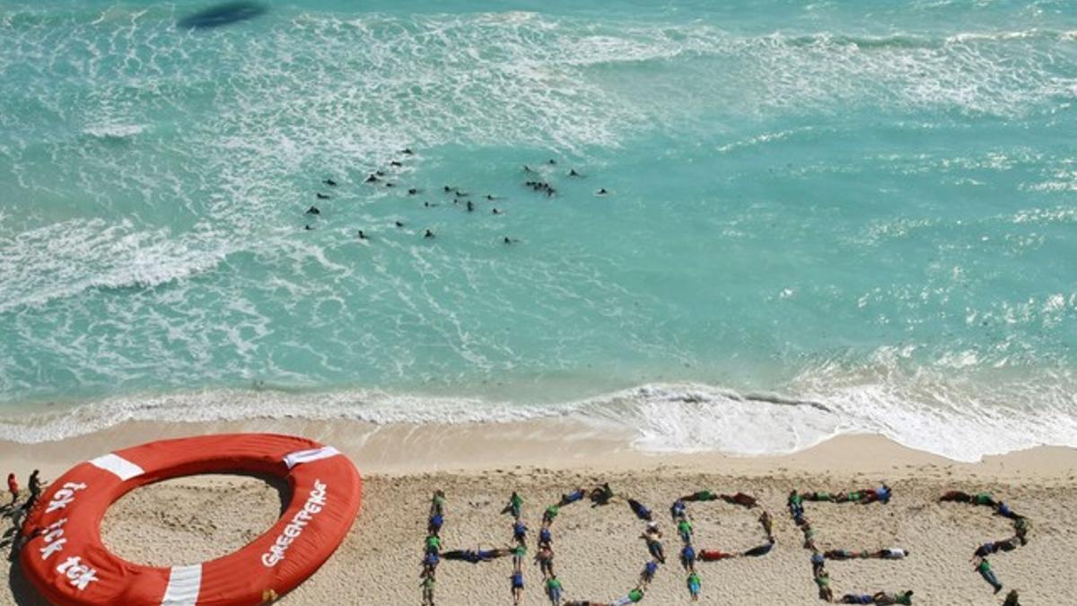Activistas de Greenpeace forman la palabra 'hope' (esperanza) en una playa de Cancún.