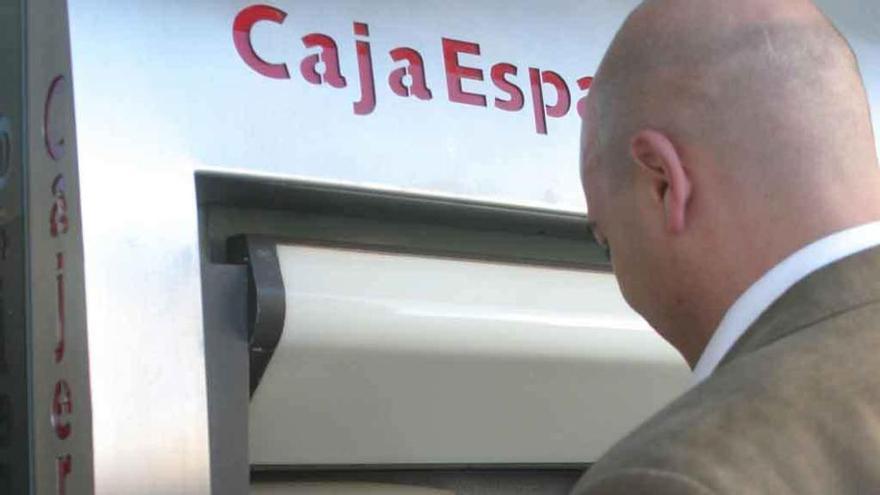 Un hombre saca dinero de un cajero de Caja España.