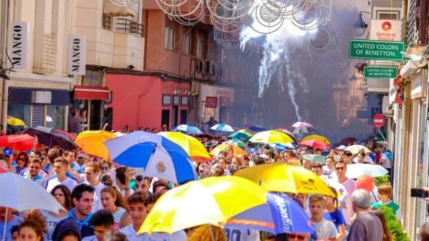 Uno de los habituales pasacalles de percusión y dulzaina, y la multitud corriendo con paraguas para no quemarse con los petardos.