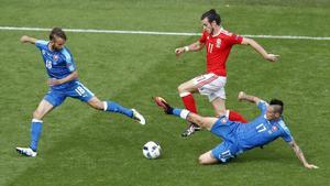 Bale conduce el balón perseguido por dos rivales en el partido inaugural de Gales