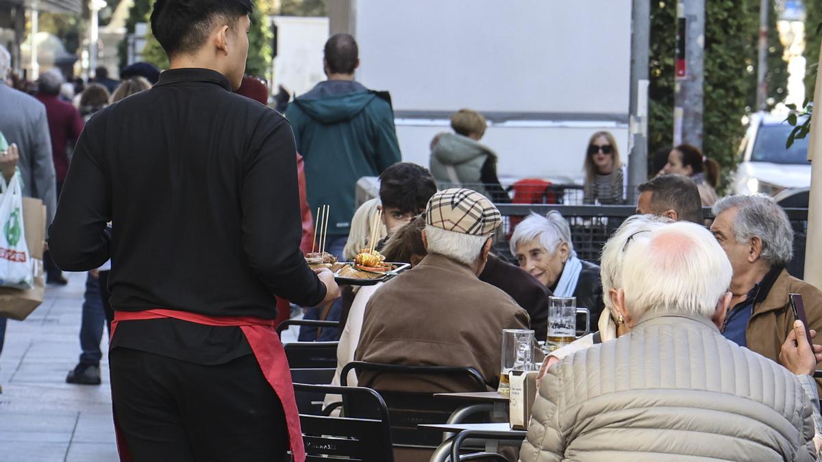 Un camarero atiende a los clientes en la terraza de un bar de Alicante.