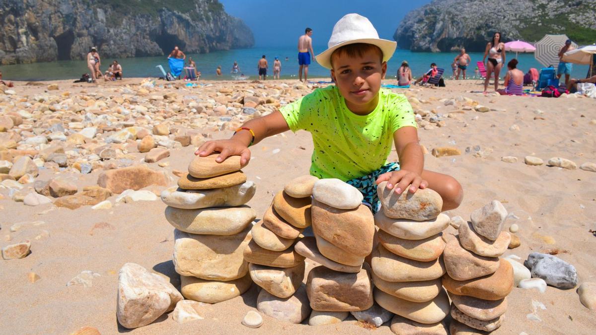 El niño Arturo Jiménez, con el pequeño muro que construyó con las piedras de la playa. | Ana Paz  Paredes
