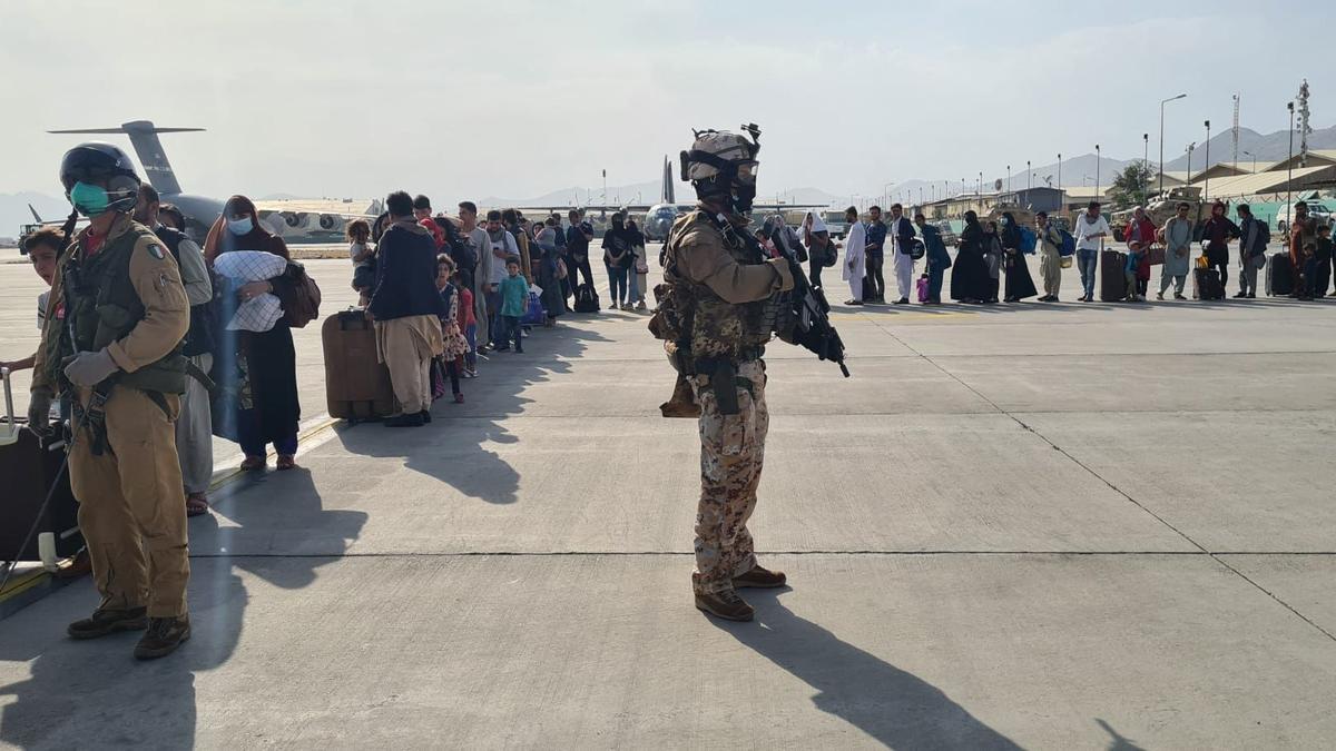Ciudadanos afganos hacen cola para subir a un avión militar italiano en el aeropuerto de Kabul