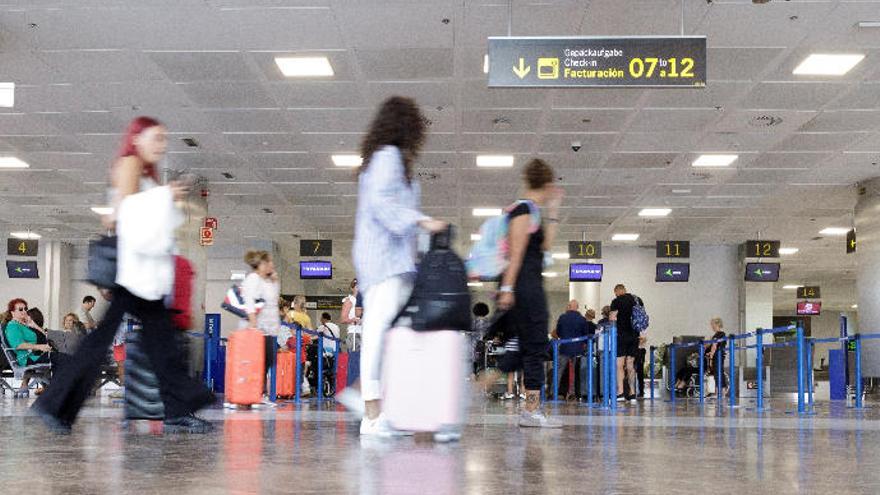 Pasajeros en el aeropuerto de Tenerife Sur pasan ante los mostradores de facturación de Ryanair.