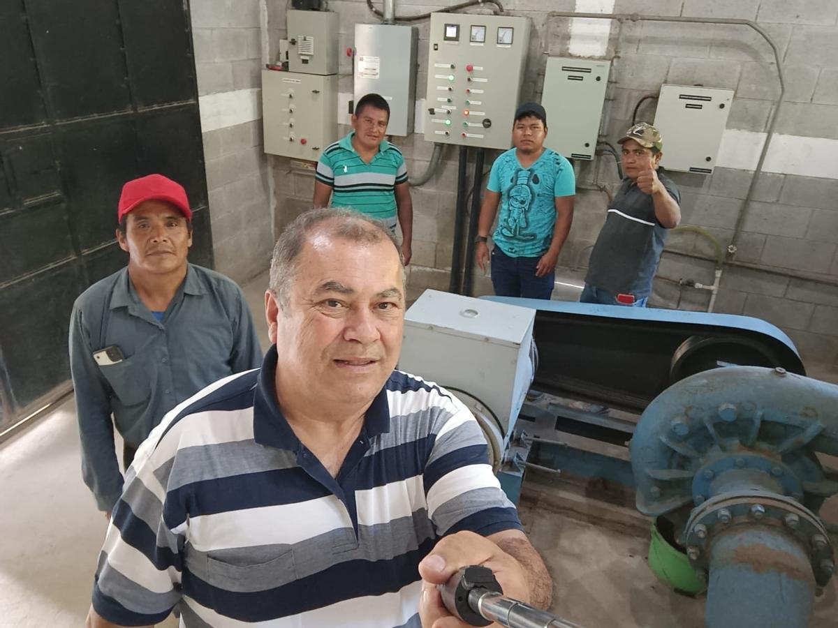 Lolo Rodríguez junto con miembros las comunidades muestran la turbina de la central hidroeléctrica.