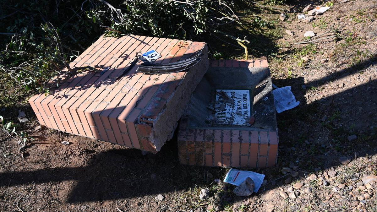 Restos de la matrícula y del parachoques del coche de la víctima, sobre el monolito de Tres Arroyos, en el lugar del crimen.