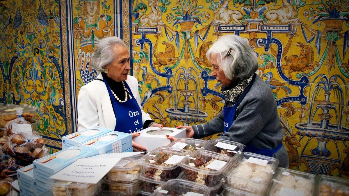Dos voluntarias venden dulces de los conventos de Sevilla en el Real Alcázar.
