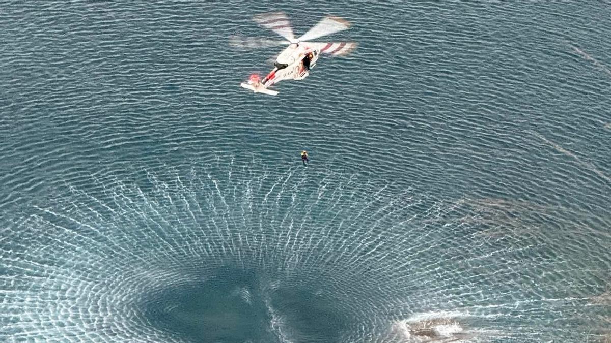 Momento en el que el rescatador baja hacia los bañistas, que estaban agarrados a su tabla de paddle surf