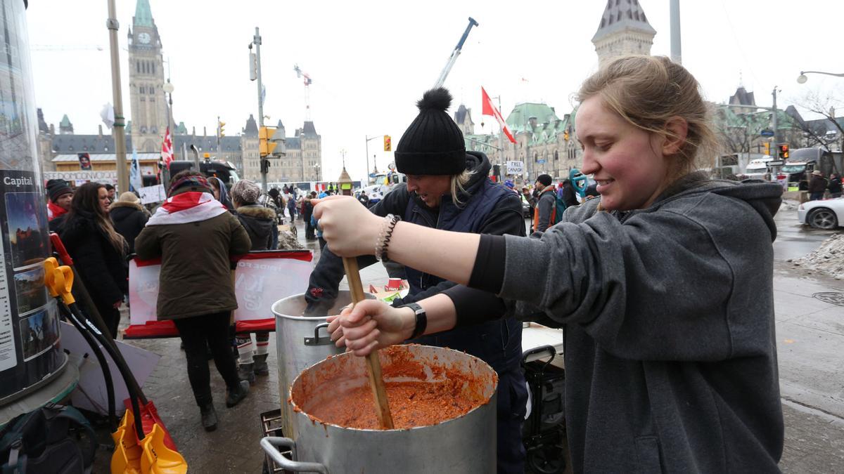 Two supporters prepare lunch as demonstrators continue to protest the vaccine mandates implemented by Prime Minister Justin Trudeau on February 8, 2022 in Ottawa, Canada. (Photo by Dave Chan / AFP)