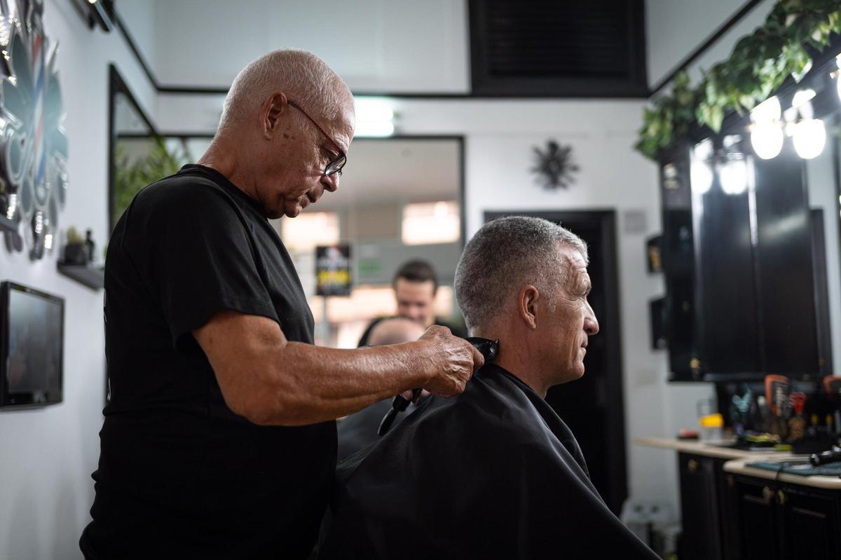 Un peluquero atiende a un cliente.