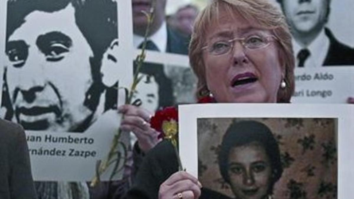 La expresidenta Michelle Bachelet, con fotos de víctimas del régimen de Pinochet, el martes en Santiago.
