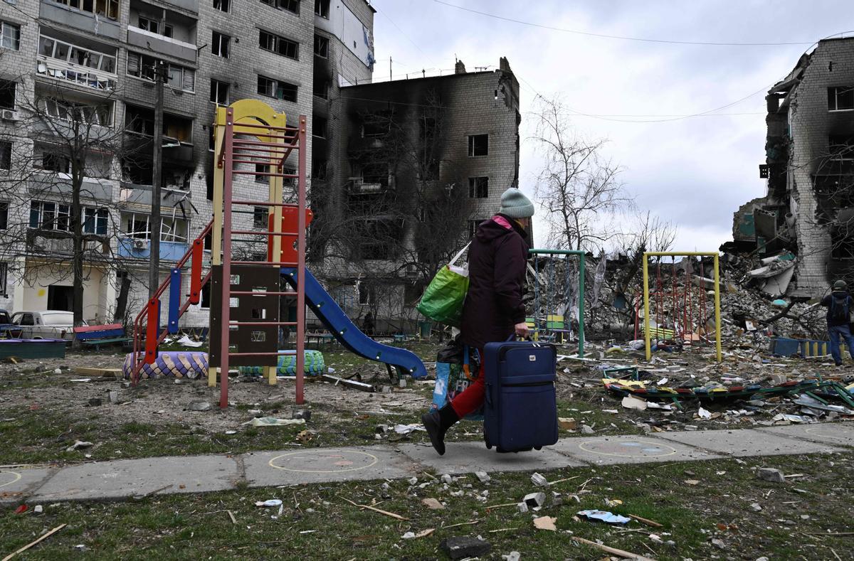 Una mujer local lleva pertenencias de una casa dañada en la ciudad de Borodianka, al noroeste de Kiev,  durante la invasión militar rusa lanzada contra Ucrania. - La retirada rusa la semana pasada ha dejado pistas de la batalla librada para mantener el control de Borodianka, a solo 50 kilómetros (30 millas) al noroeste de la capital ucraniana, Kiev.