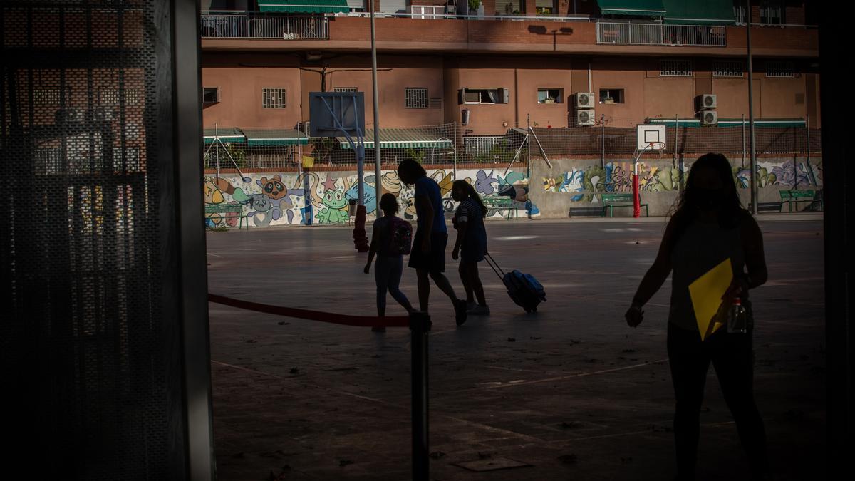 Padres y alumnos en el patio de un colegio.