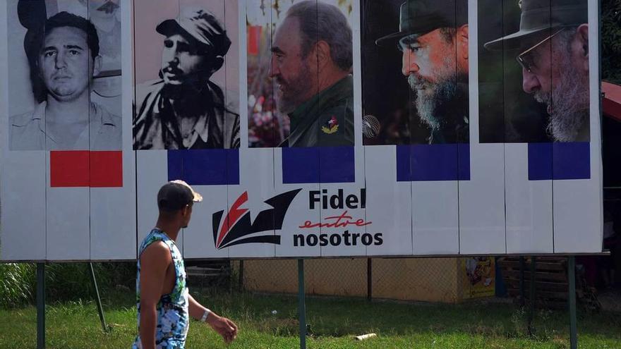 Un cubano pasa ante un cartel con varias imágenes de Castro.
