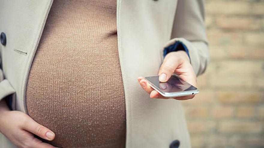 Una mujer embarazada consulta su móvil.