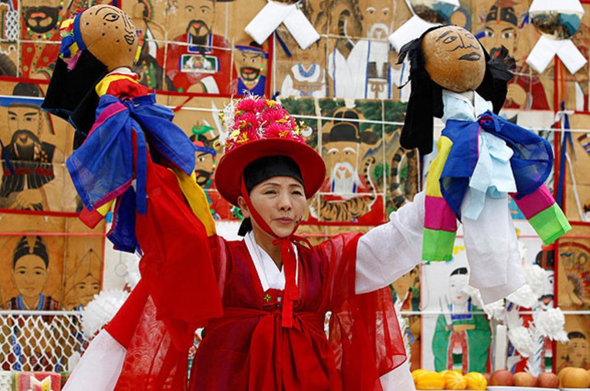 Una dona resa durant una cerimònia en una barca, amb objectes que atrauen la bona sort i allunyen els dimonis que amenacen els pescadors, a Seül.