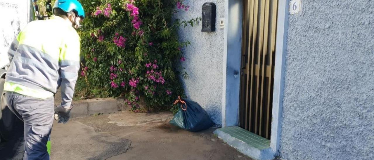 Un operario de la empresa Valoriza recoge la basura que deja un vecino a la puerta de su domicilio en la Cruz de La Gallega (Suroeste).