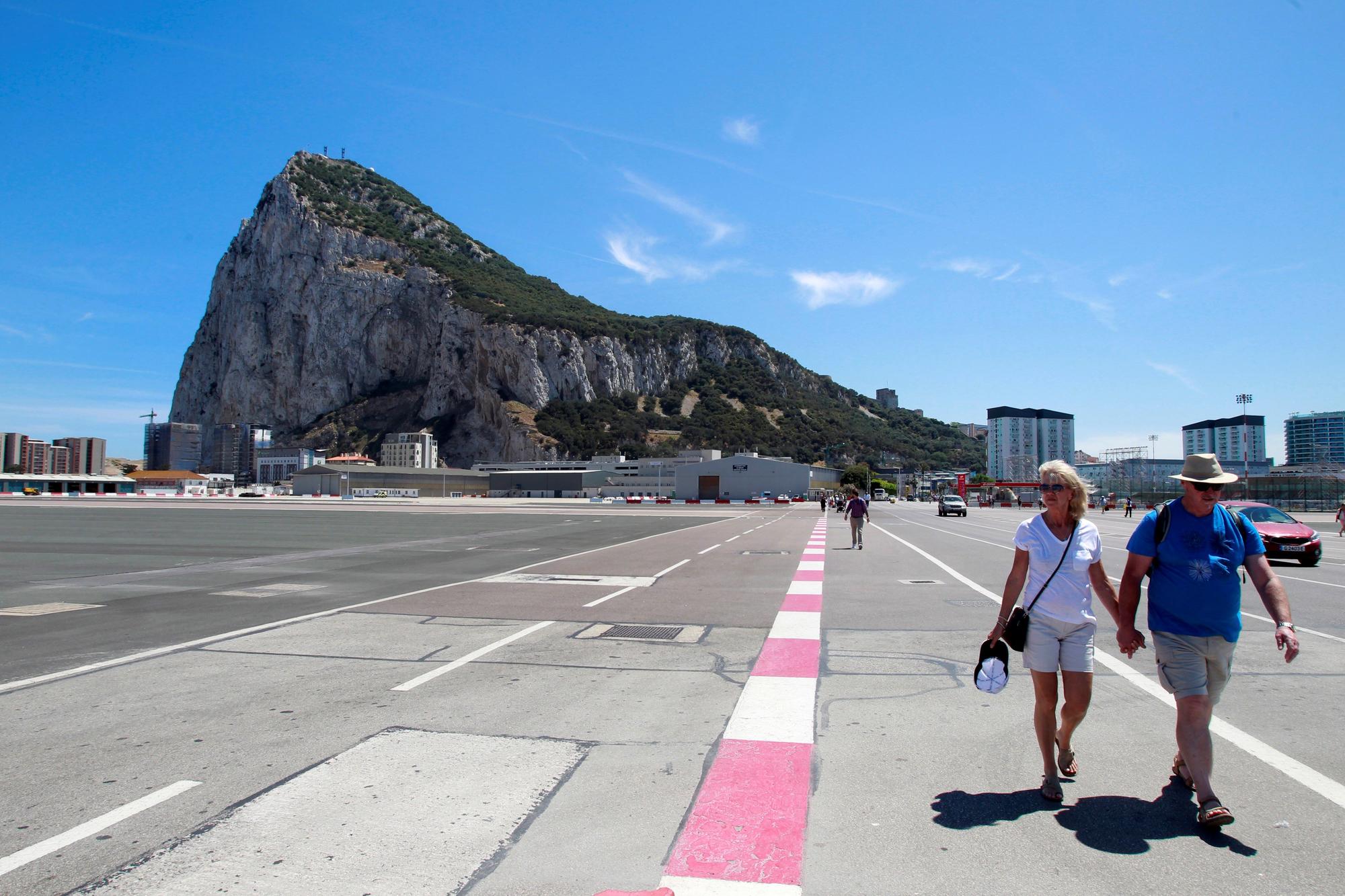 Dos turistas caminan por la pista del aeropuerto de Gibraltar