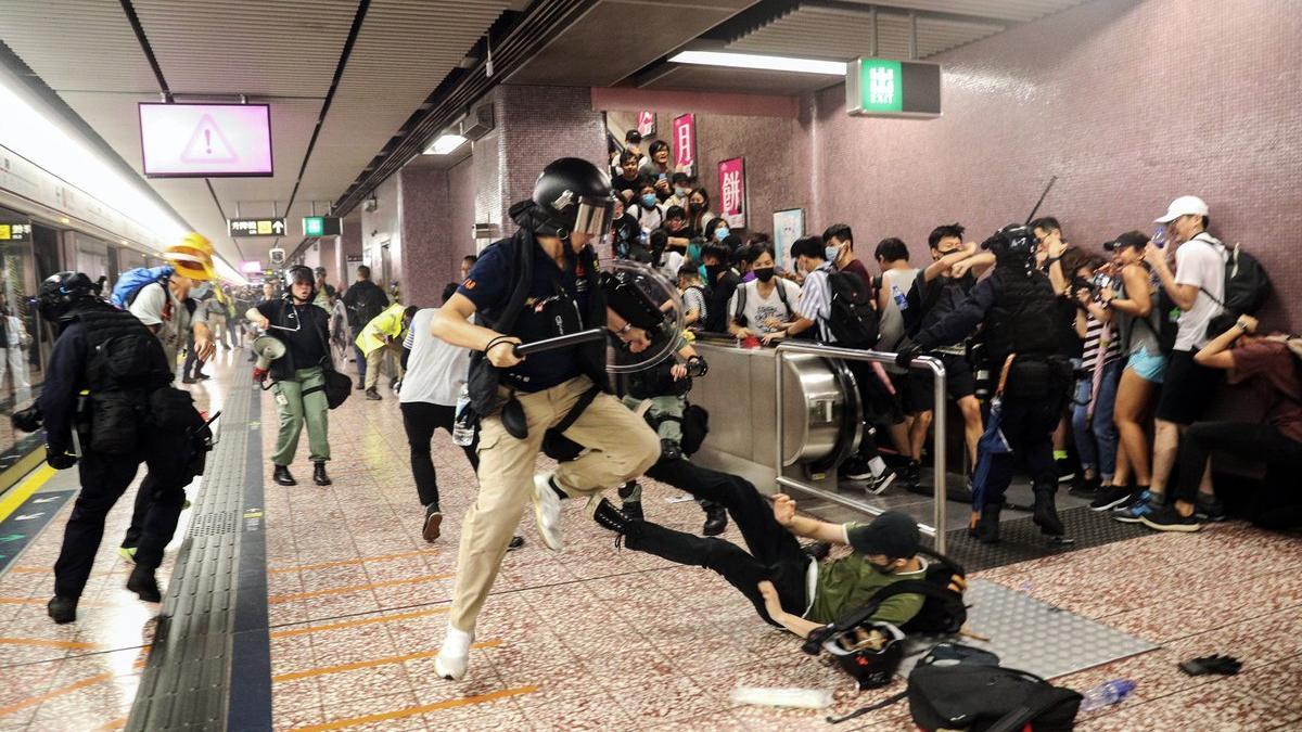 Agentes de policía cargan contra ciudadanos que venían de la manifestación, en la estación de metro Prince Edward de Hong Kong, este sábado.