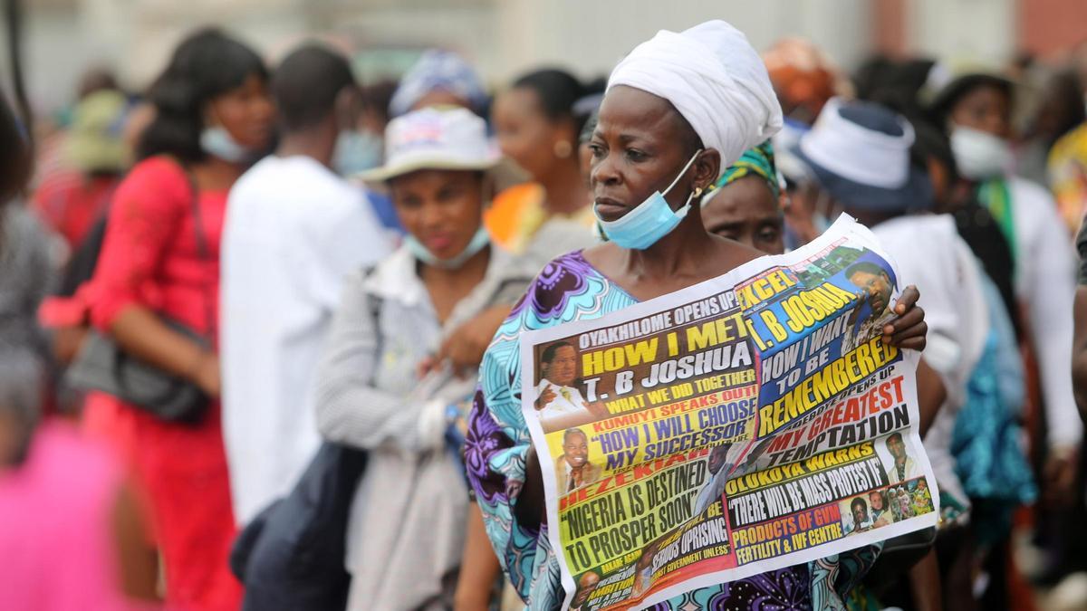 Una mujer porta un periódico en Nigeria que da cuenta de la muerte, en 2021, del evangelista TB Joshua.