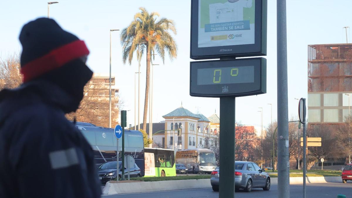 Un hombre abrigado contra el frío pasa junto a un termómetro que marca cero grados en Córdoba.