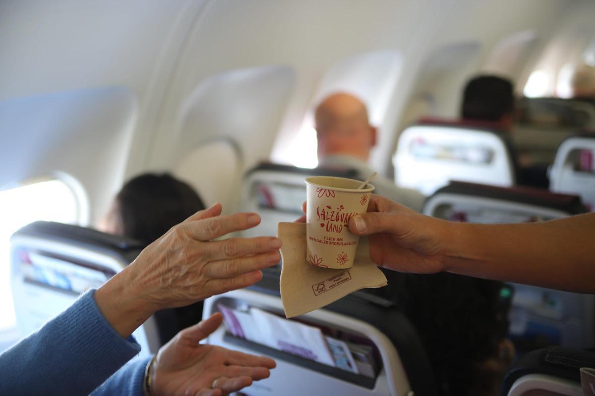 Ein Purser überreicht einem Fluggast ein Getränk (1)