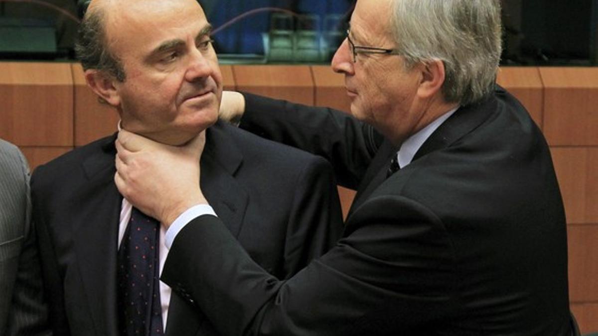 Juncker (derecha) coge del cuello a Guindos durante su encuentro en Bruselas.