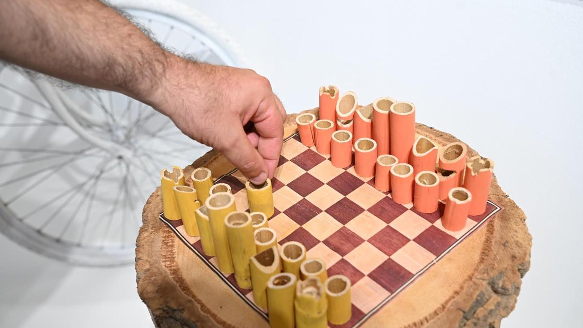 Un tablero de ajedrez hecho con el tronco de una palmera y fichas con cañas