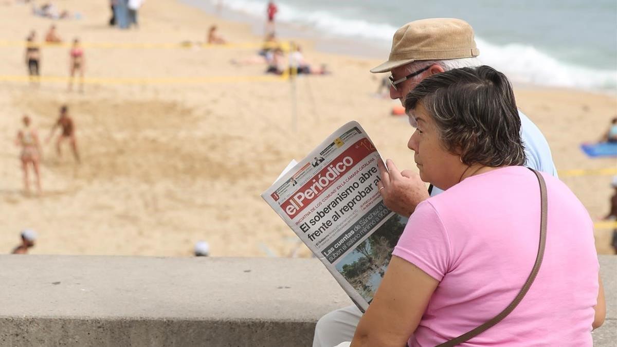 Una pareja lee El Periódico en Barcelona