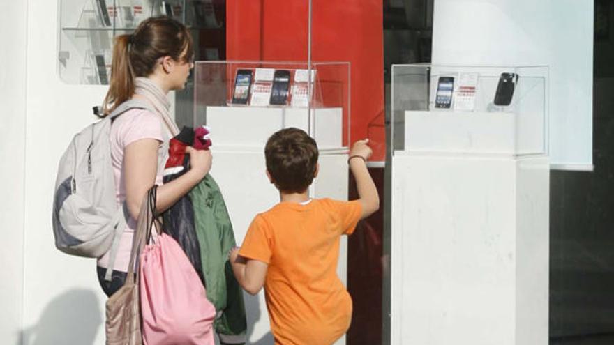 Dos menores observan varios móviles en una tienda