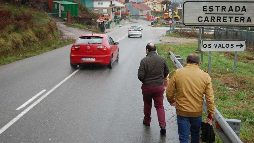 Dos personas caminan por la carretera N-555 en la parroquia de Vilar, donde reclaman aceras. // FdV