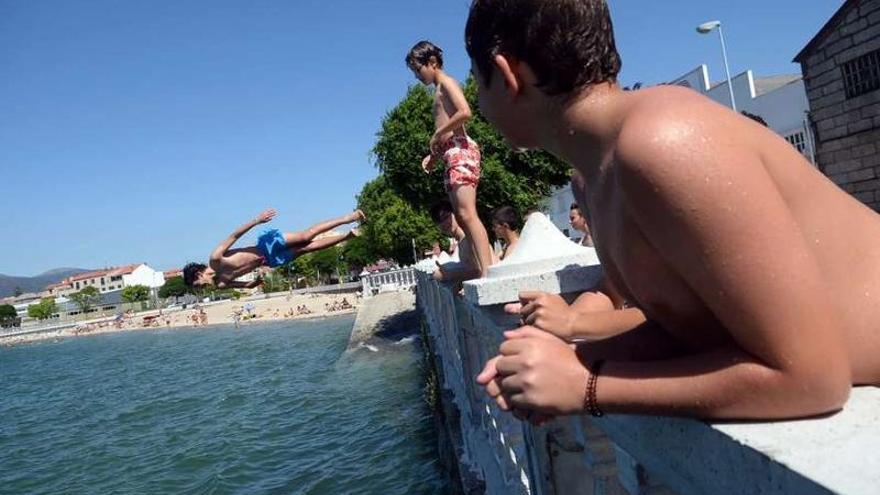 Jóvenes jugando con un balón en el agua en O Campanario.