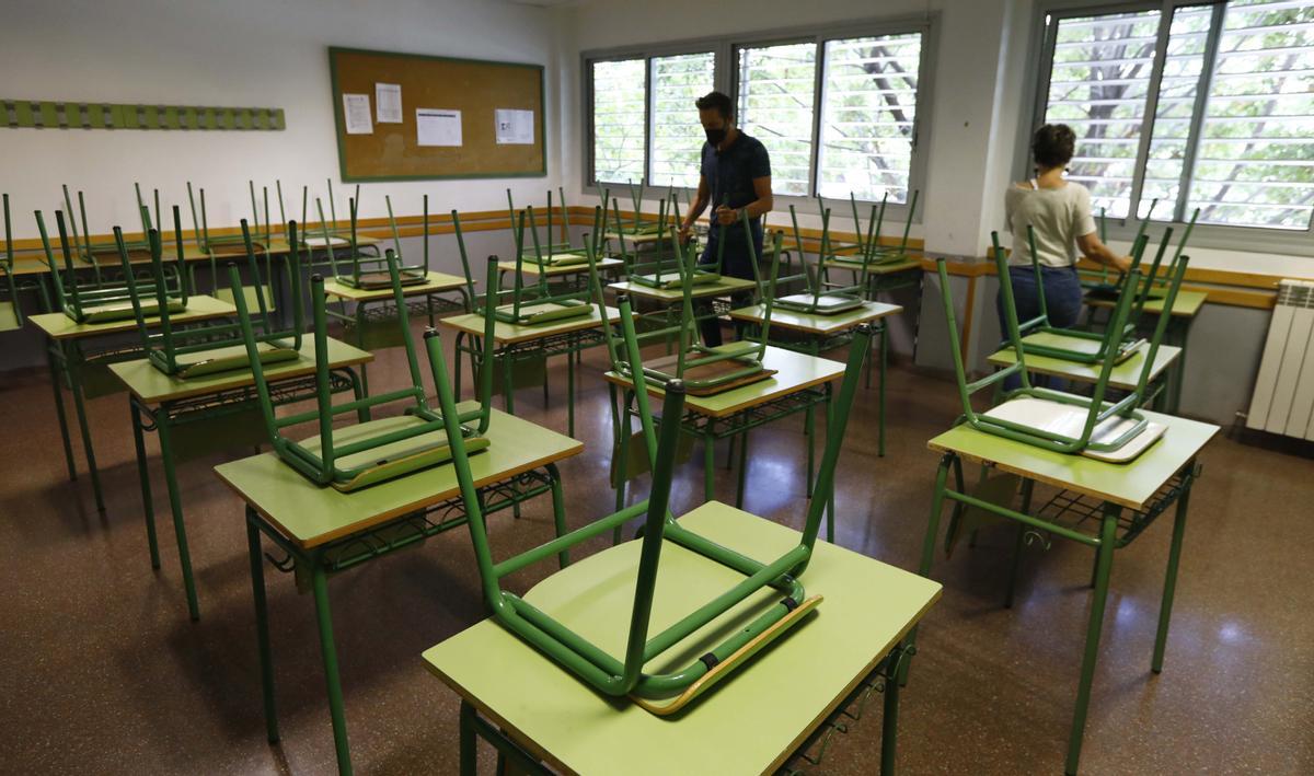 Dos profesores del instituto de La Azucarera, en Zaragoza, ordenan una clase del centro antes de cerrar su puerta definitivamente, este martes.
