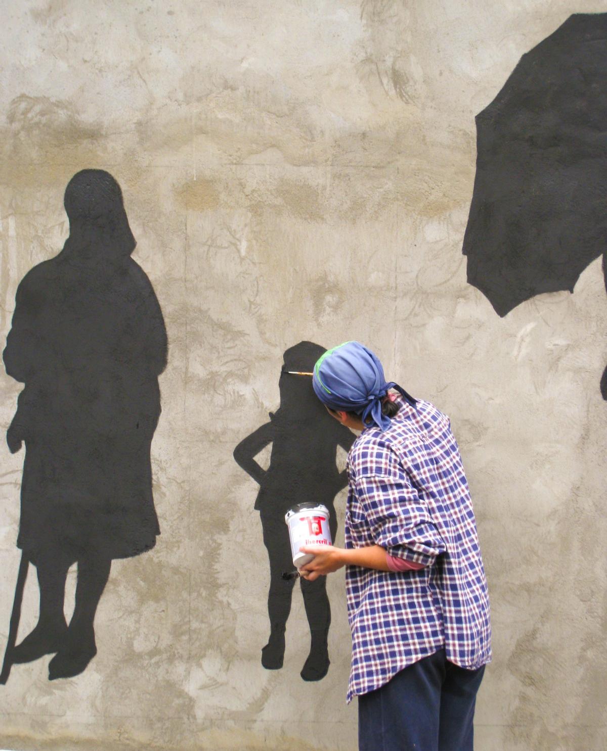 La artista asturiana, el día que comenzó a pintar el muro con algunos vecinos del pueblo.