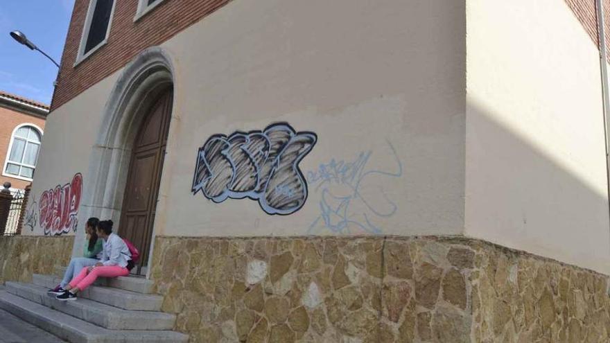 Dos jóvenes en la escalera de la capilla del colegio San Vicente de Paúl, donde están los grafitis.