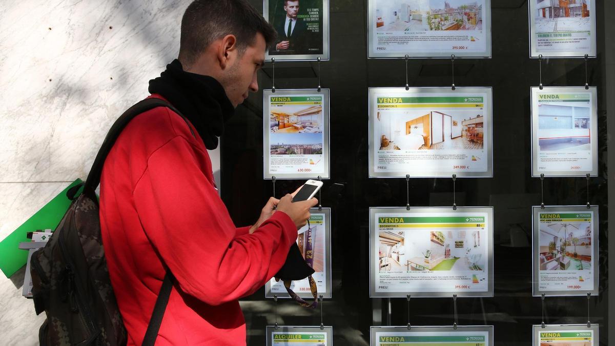 Un joven apunta teléfonos en una agencia inmobiliaria de Barcelona.