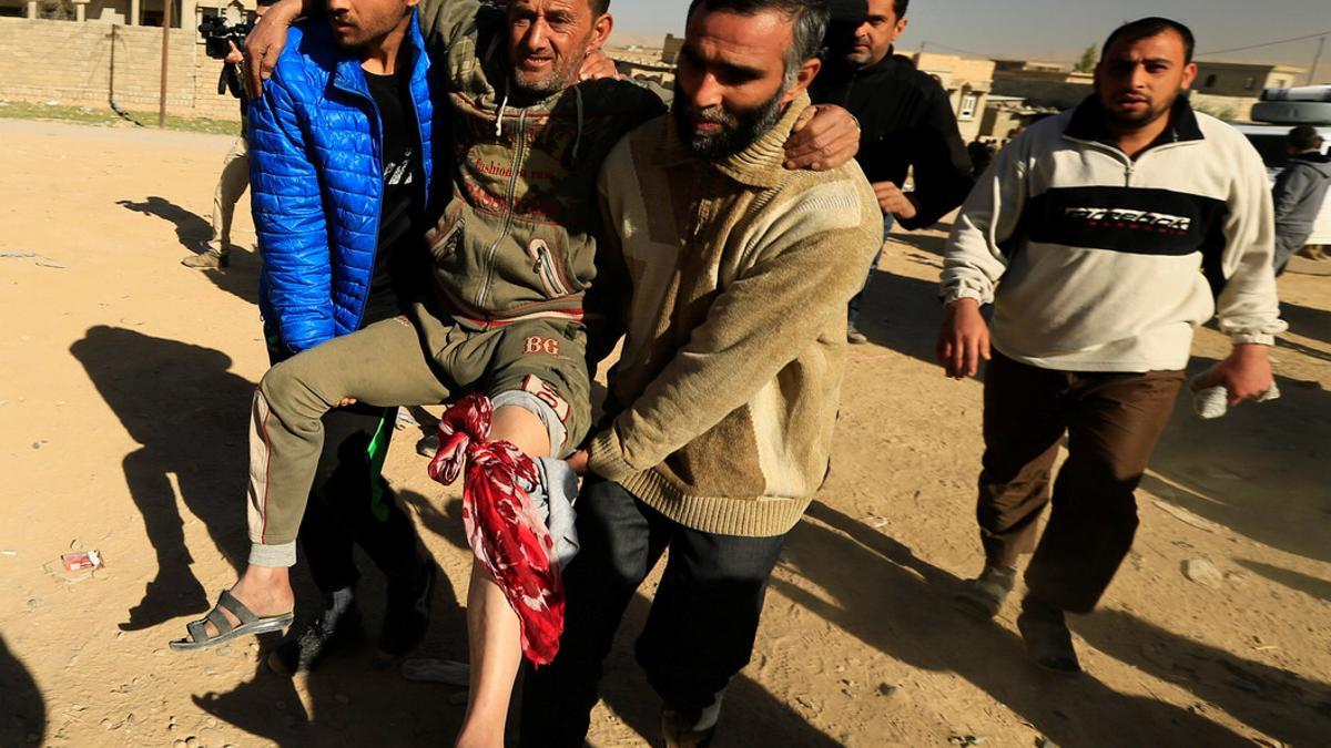 People carry a displaced man who was injured during clashes, while he flees from Islamic State militants of Tahrir neighborhood in Mosul